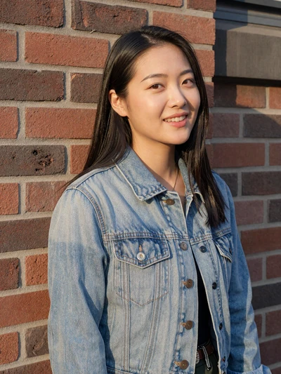 Lily, 30, a real LunaMeet user smiling against a brick wall at golden hour, shown on the FAQ page